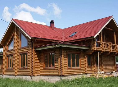 Двухэтажный деревянный дом с балконом из оцилиндрованного бревна